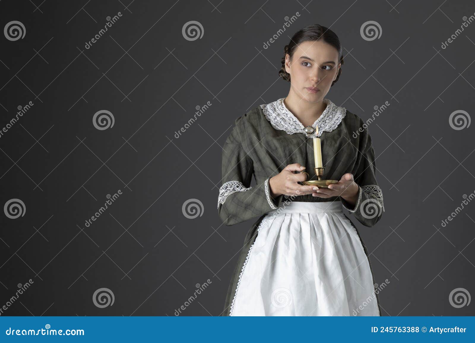 a working class victorian woman wearing a dark green check bodice and skirt with an apron and holding a candle.