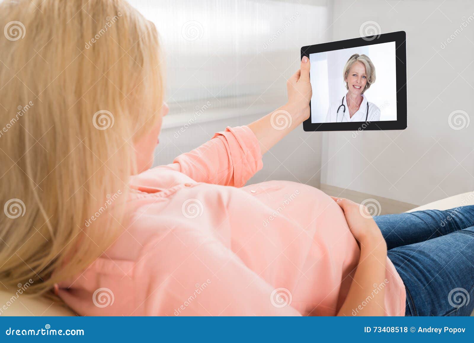 Video comunicazione della donna incinta con il dottore On Tablet Computer. Giovane video comunicazione delle donne incinte con medico femminile sul computer della compressa a casa