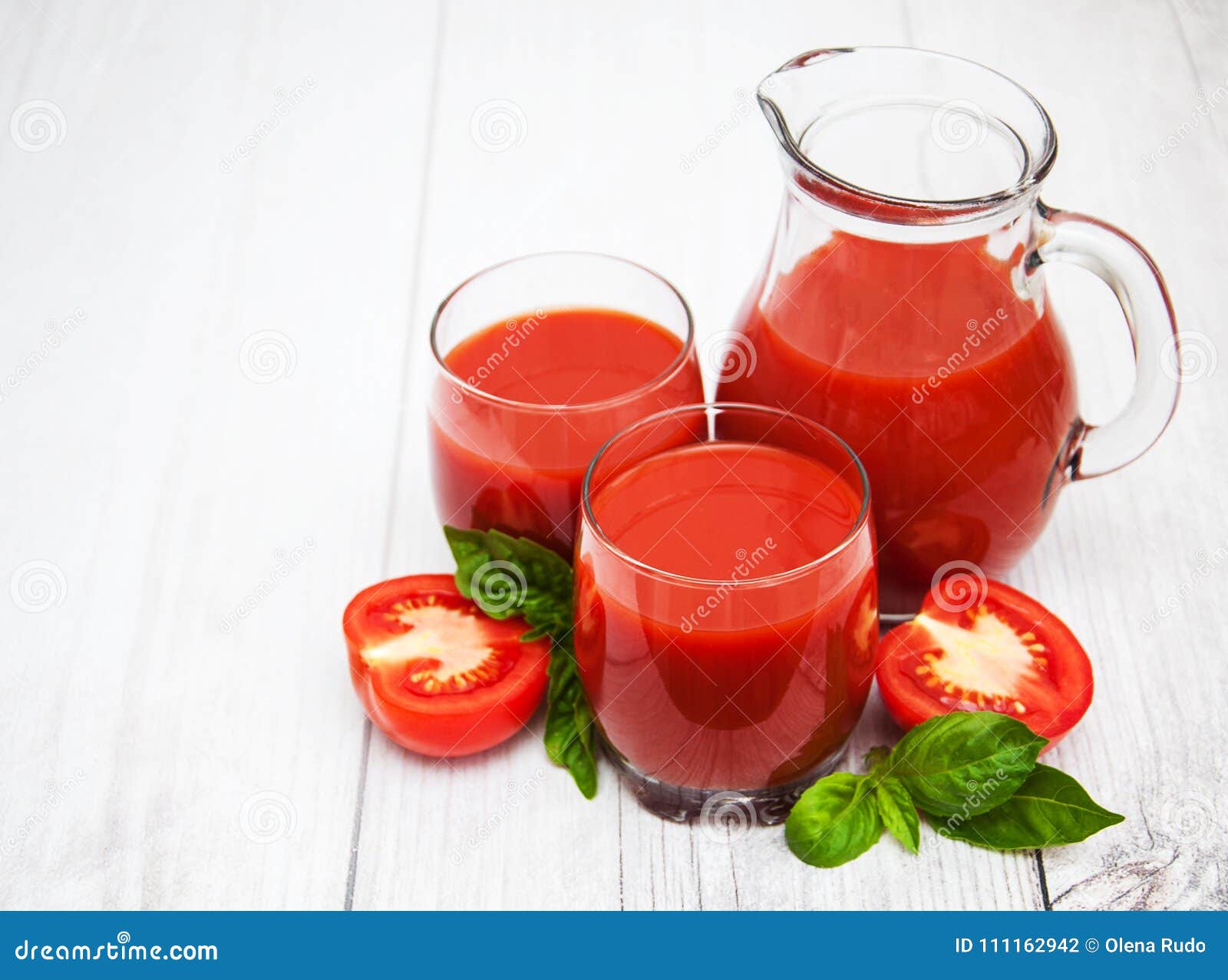 Vidrios con el jugo de tomate y los tomates frescos en una tabla