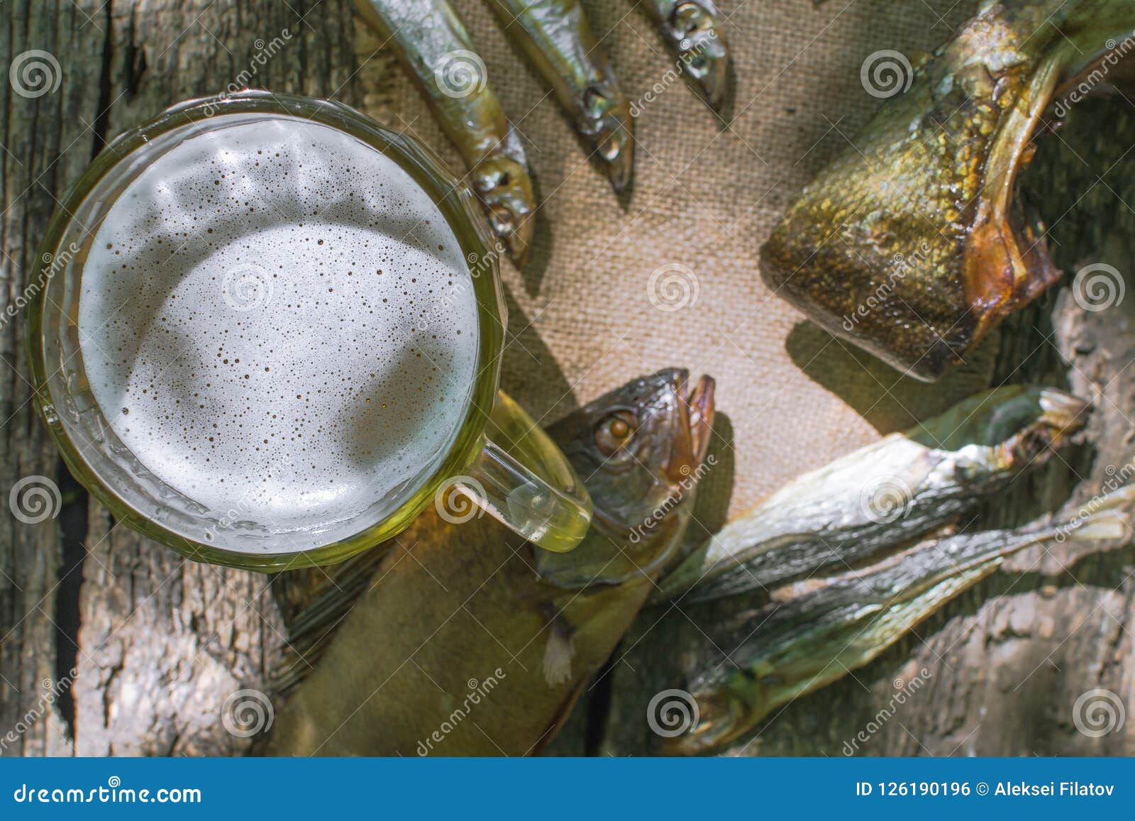Vidro da cerveja com peixes secados. Vidro da cerveja com os peixes secados no fundo de madeira no estilo rústico