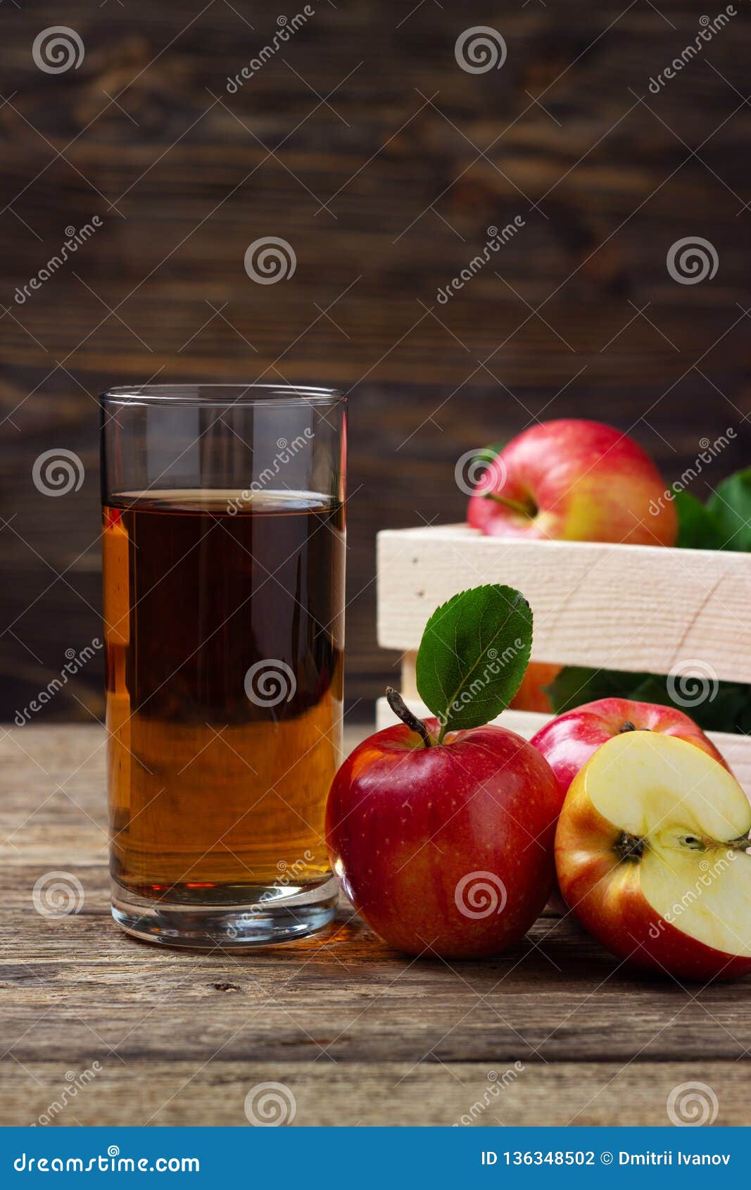 Vidro do suco de maçã com maçãs vermelhas. Vidro do suco de maçã com as maçãs vermelhas na tabela de madeira