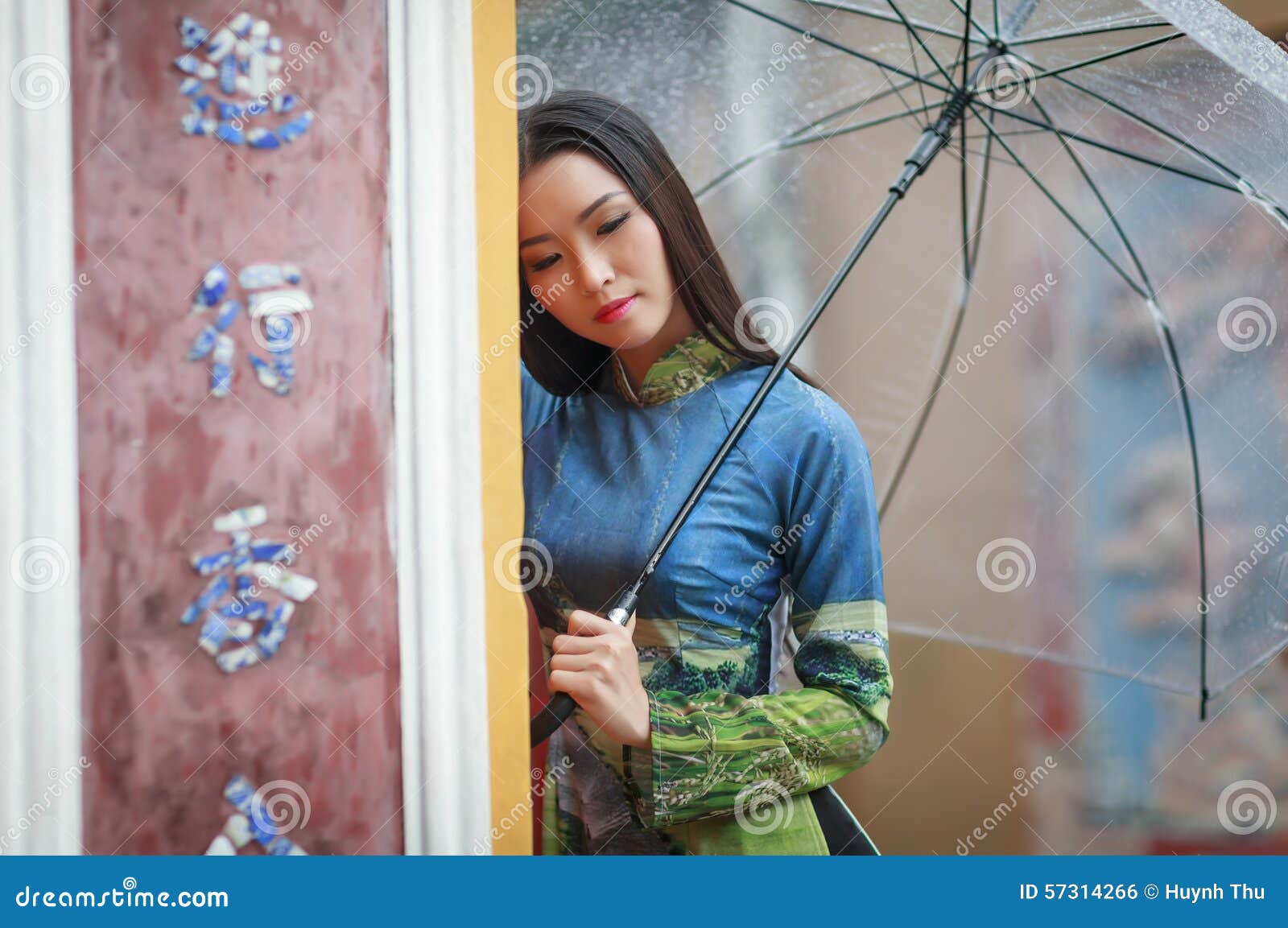 Vietnamese women wear Ao dai holding umbrella in the rain 