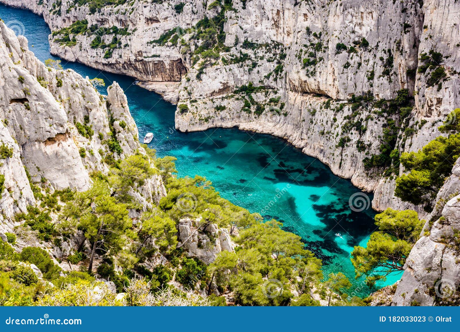 a boat is wandering in a rocky inlet with turquoise water in the calanques national park in france