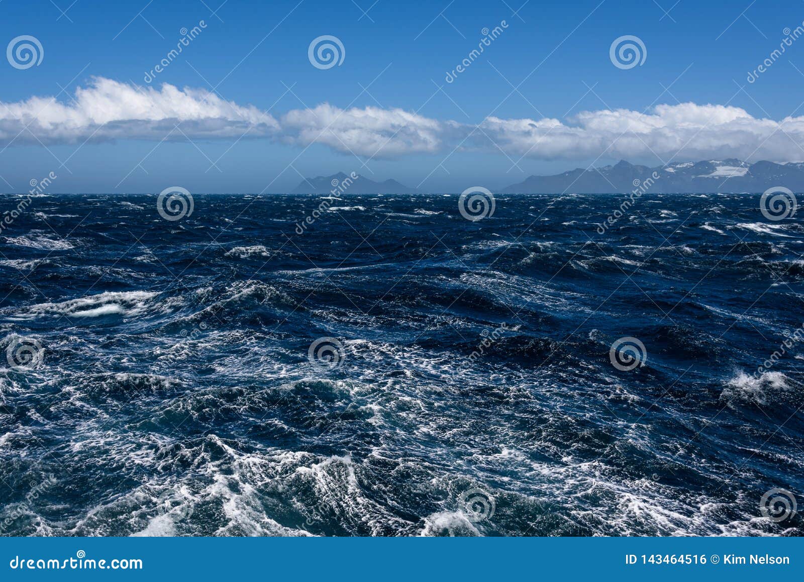 View of Atlantic Ocean and Distant Mountains, Choppy Water, Calm Blue Sky with White Clouds
