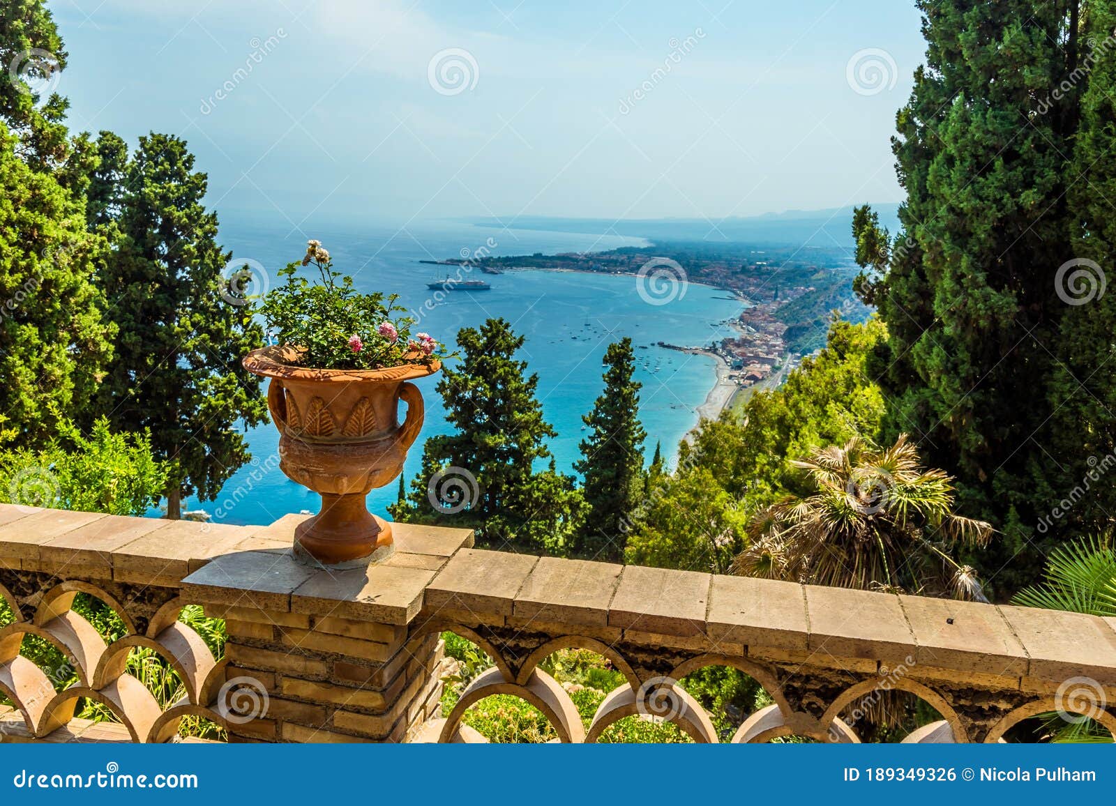 a view from a balcony in the garden of villa comunale over the shoreline of taormina, sicily
