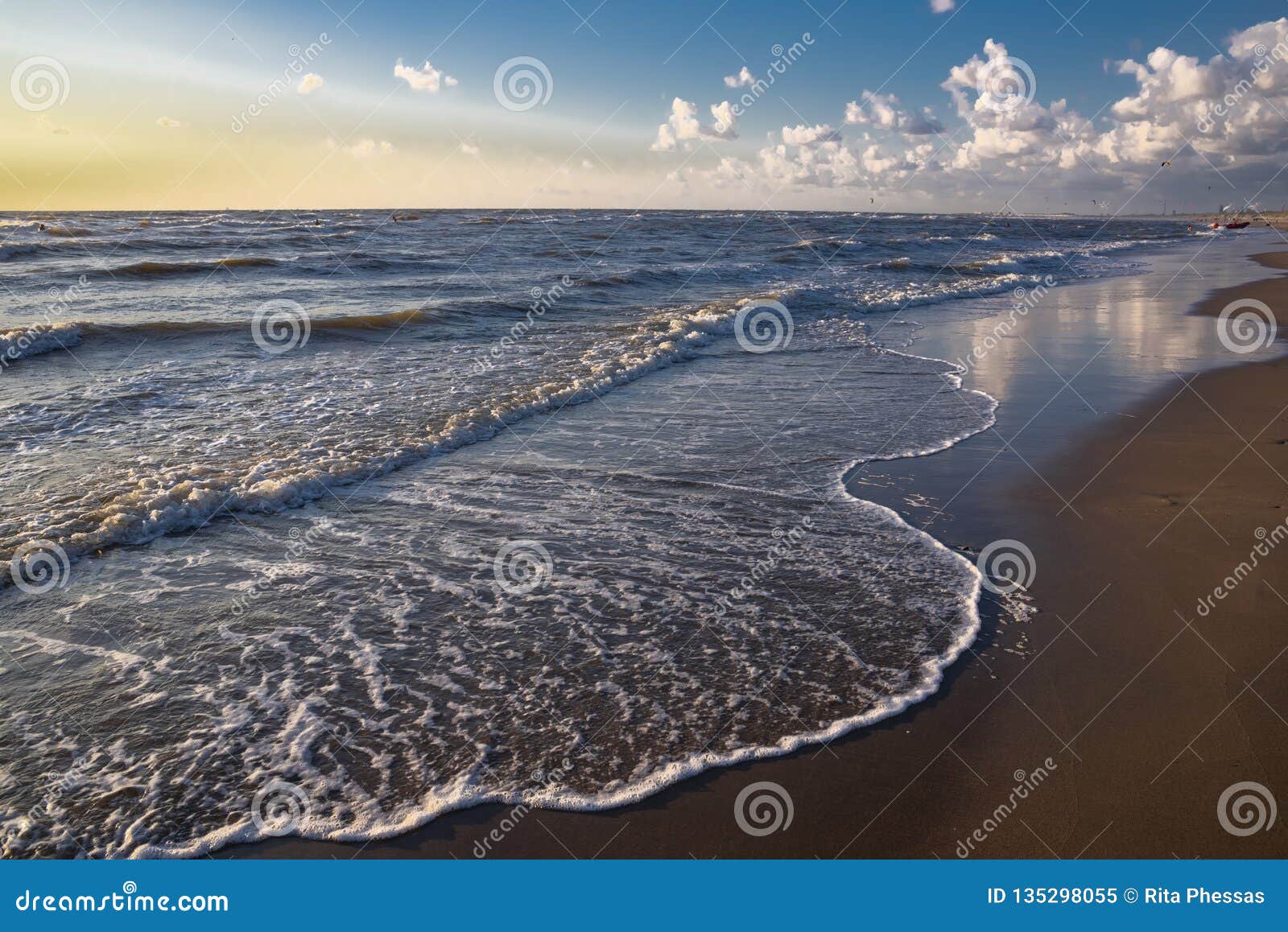 view from the beach on the white foam cups of the rising waves at high tide in the north sea, all this at sunset