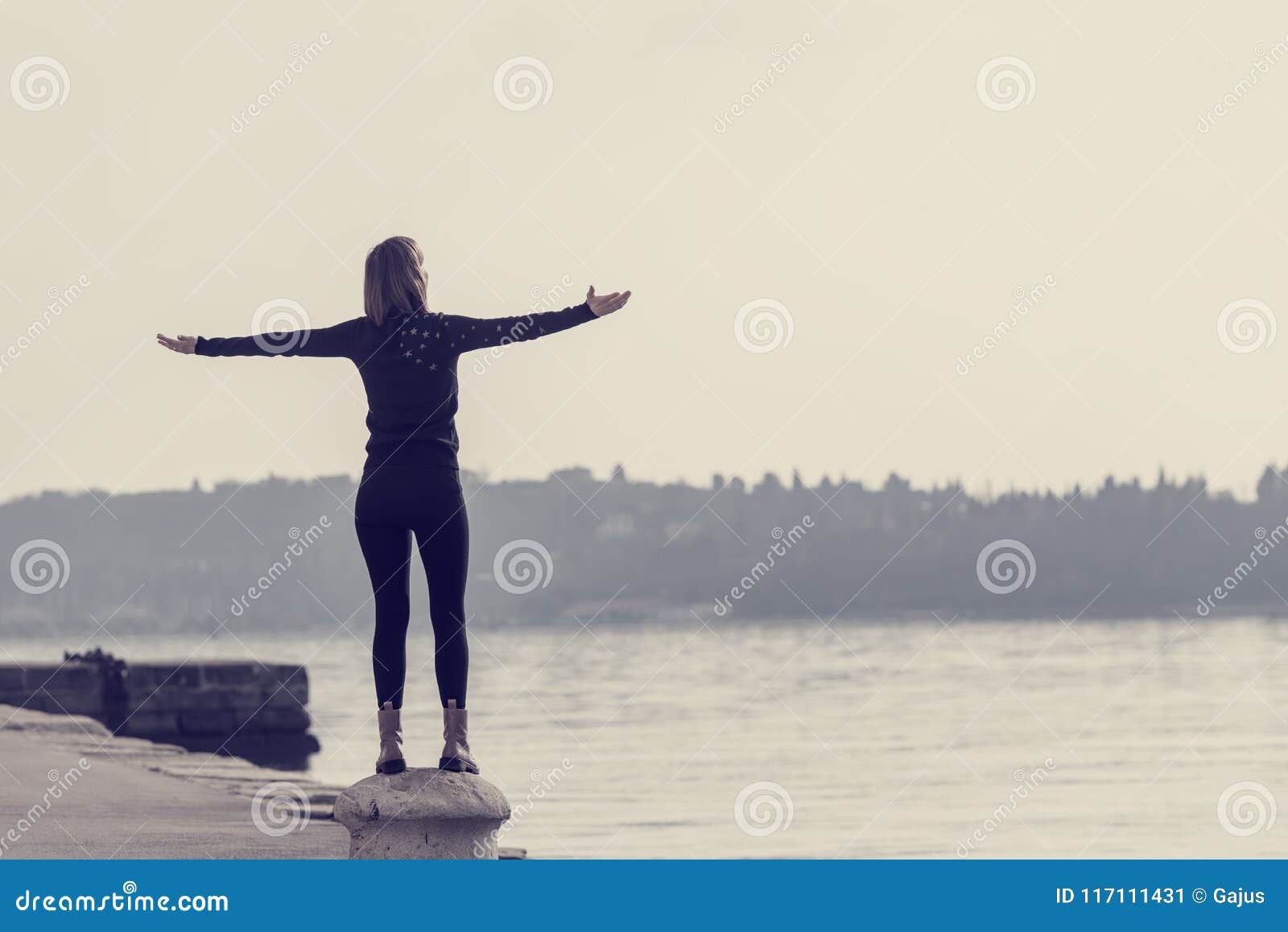 view from behind of a young woman standing on cement bollard