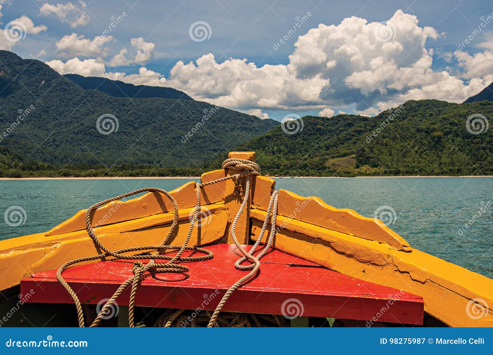 view of colorful boat bow with sea, forest and sunny sky near paraty.