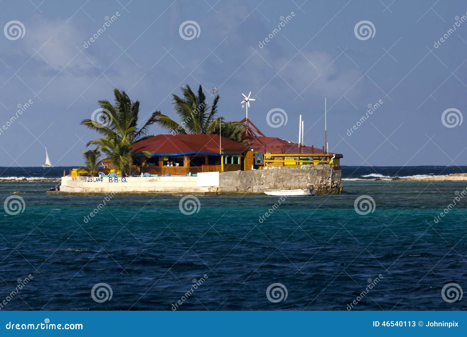 view of happy island, a tiny brightly coloured island restaurant with palm trees; the grenadines, eastern caribbean.