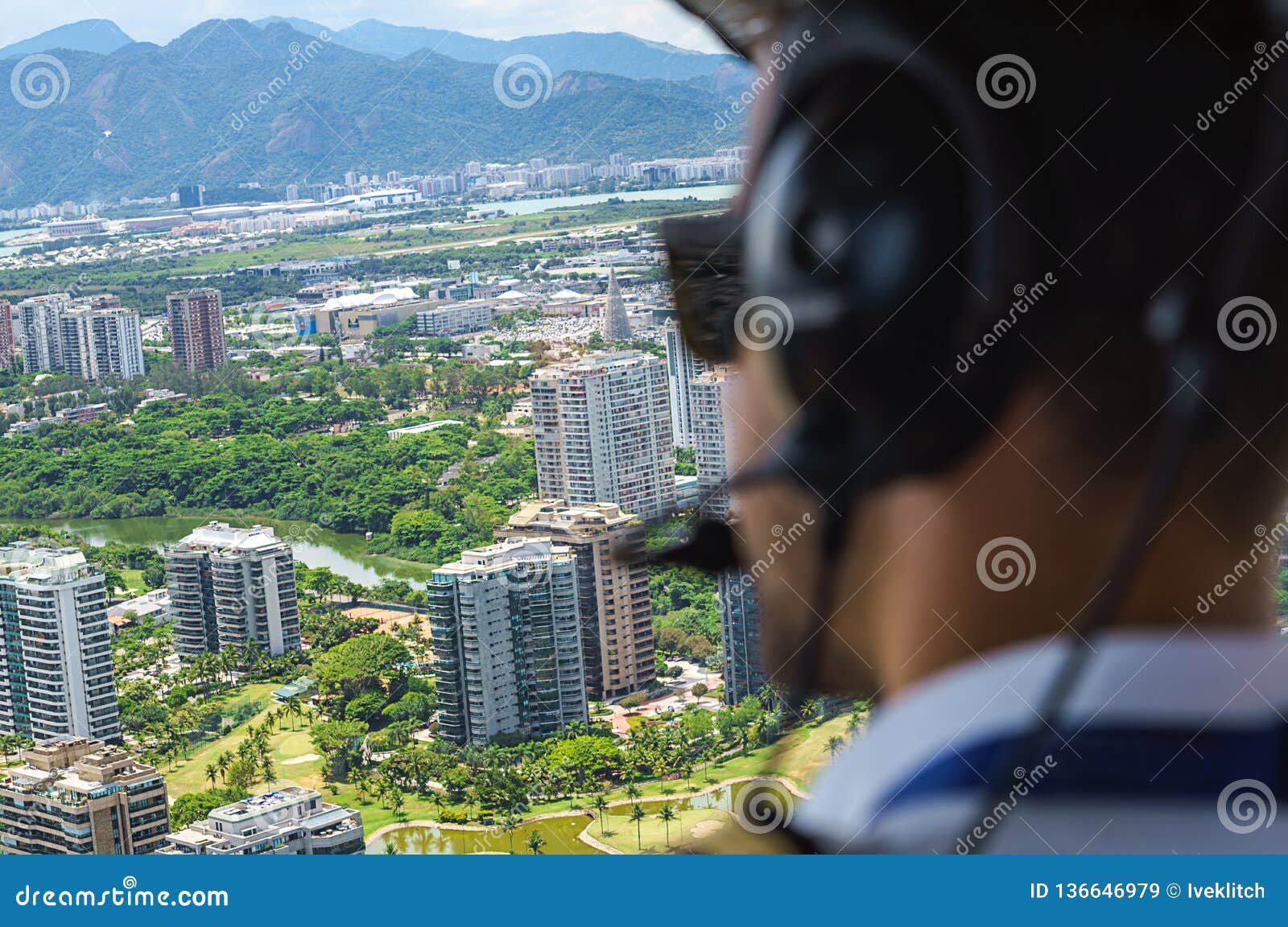 view from a helicopter cockpit flying over rio de janeiro. cockpit with pilot and control board inside the cabin in a sunny day.
