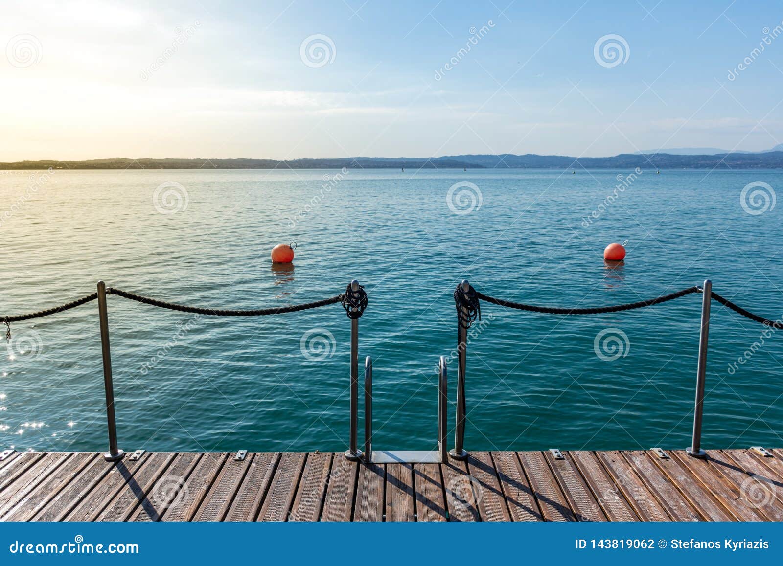 wooden jetty on peacefull garda lake, sirmione