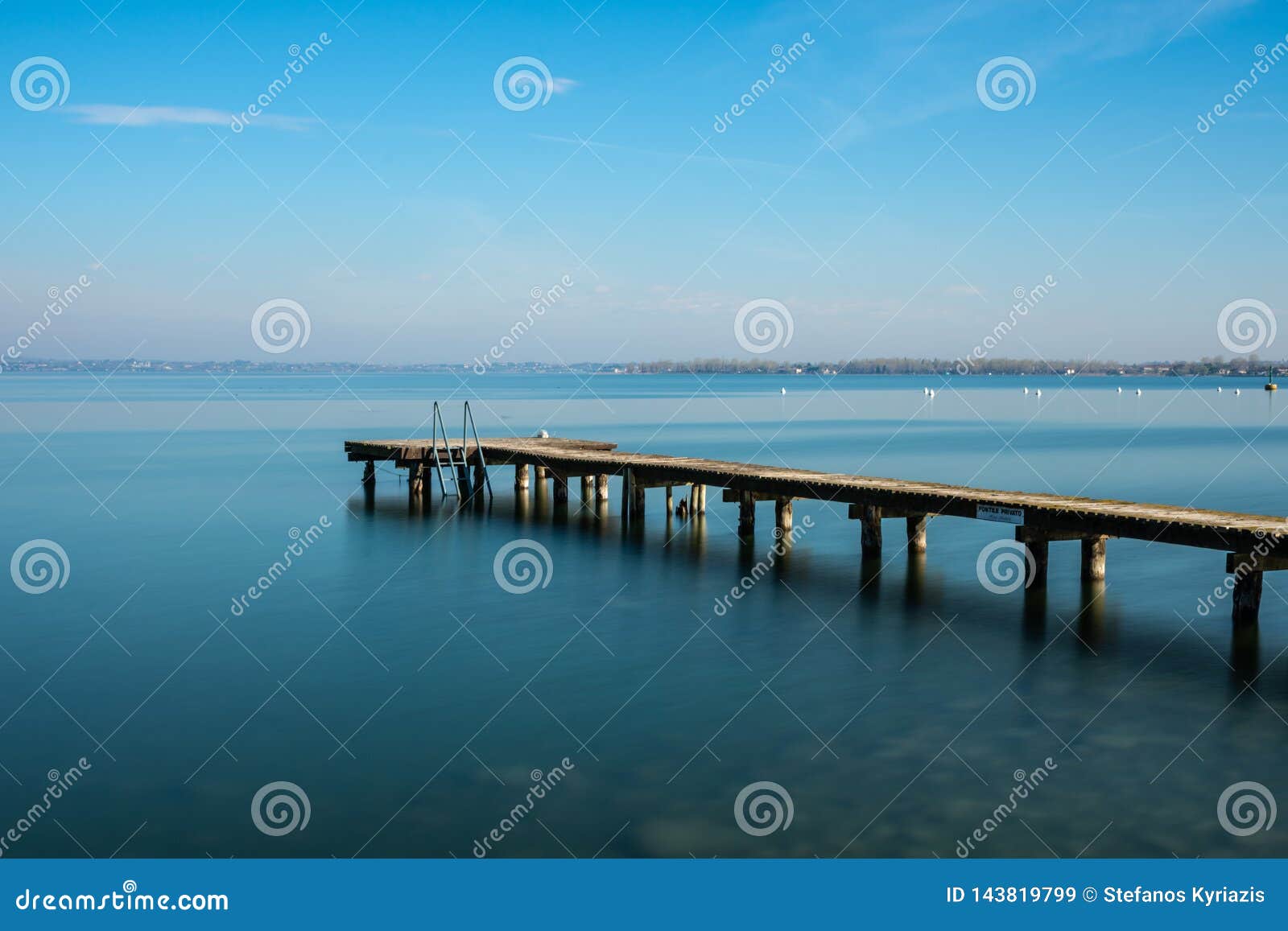 wooden jetty on peacefull garda lake, sirmione