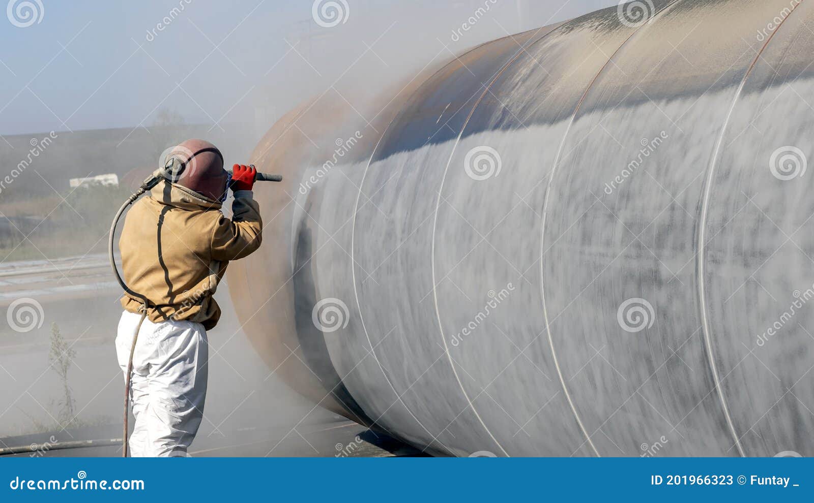 view of the manuel sandblasting to the large pipe. abrasive blasting more commonly known as sandblasting is the operation.