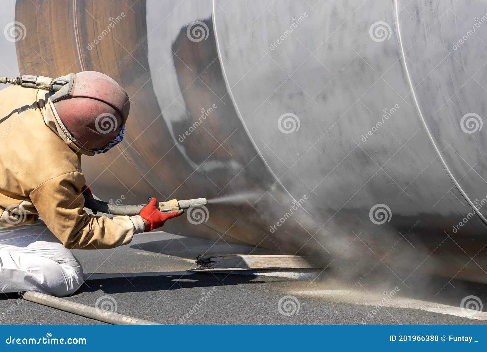 view of the manuel sandblasting to the large pipe. abrasive blasting more commonly known as sandblasting is the operation.
