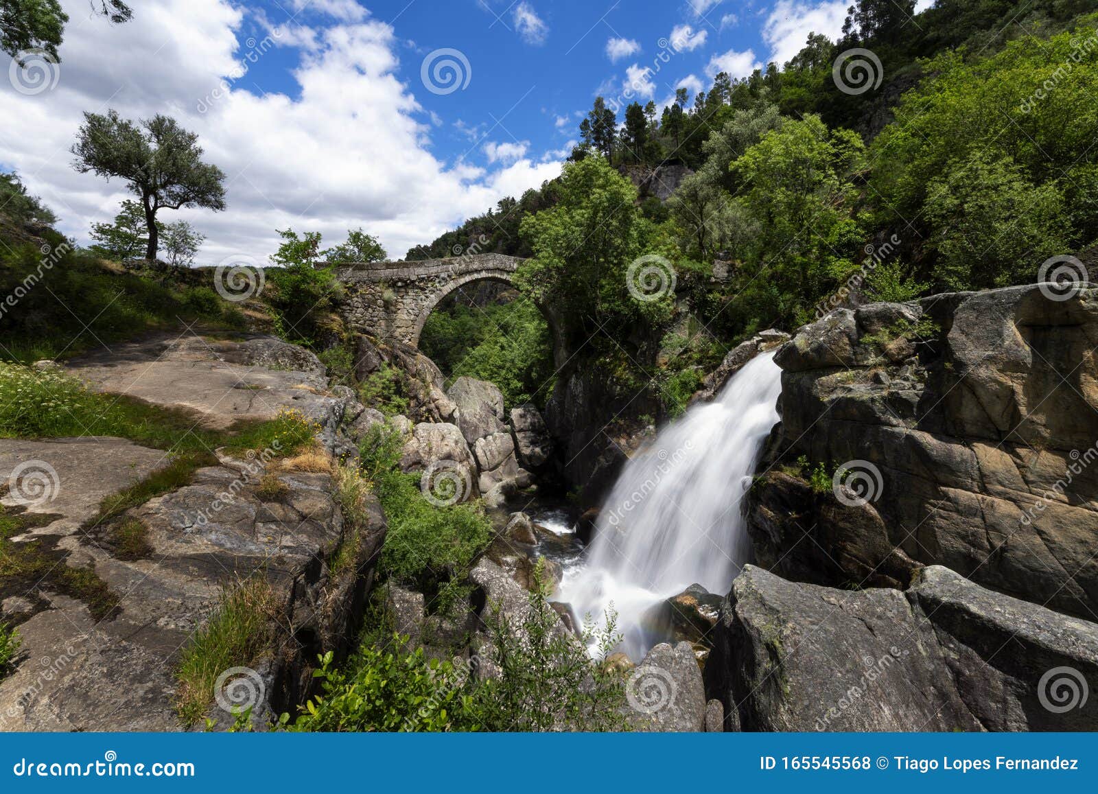 view of the mizarela bridge with a waterfall at the peneda geres national park