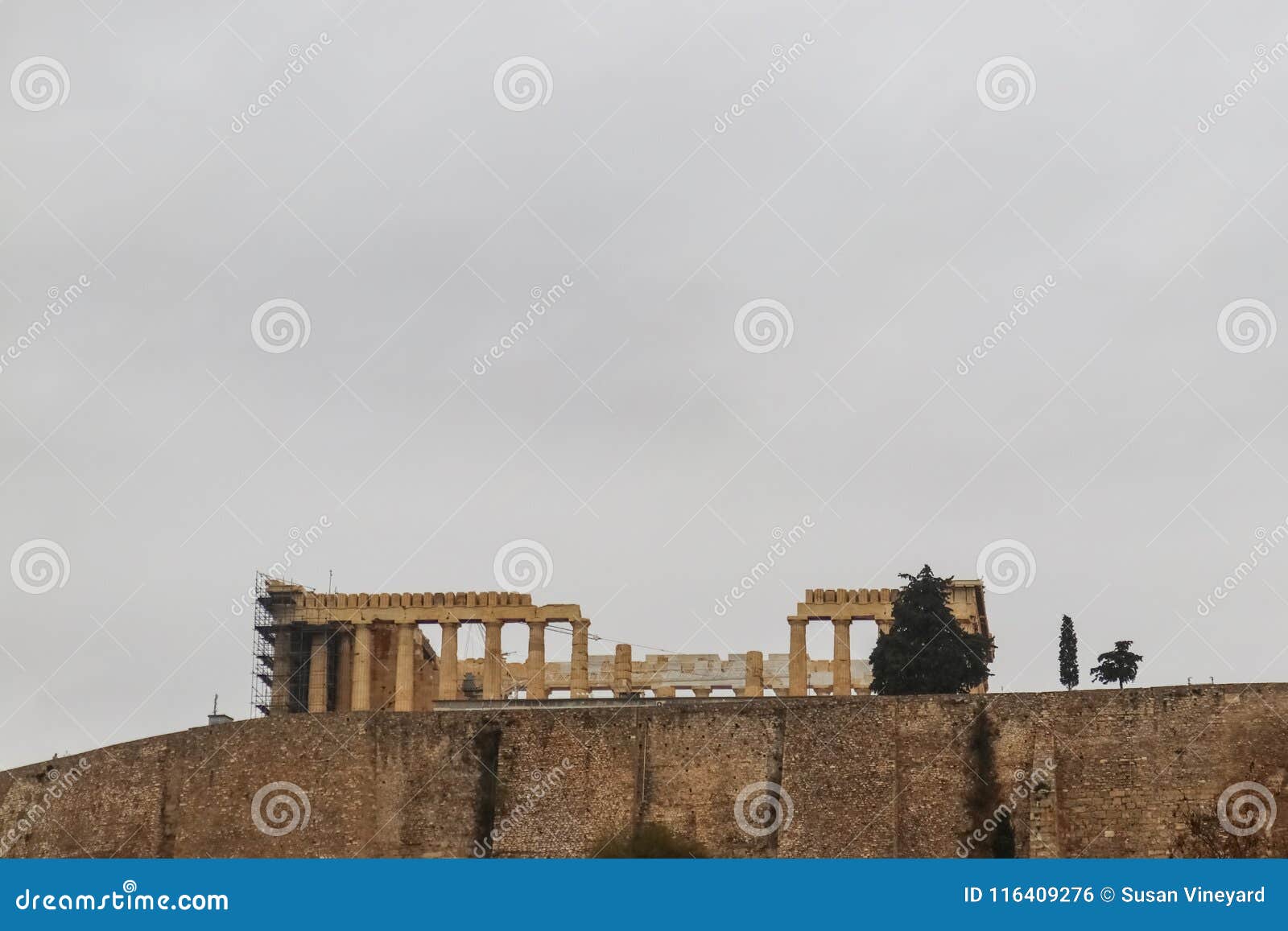 view of partenon on acropolis above retaining wall outlined against a grey sky from acropolis museum - room for copy