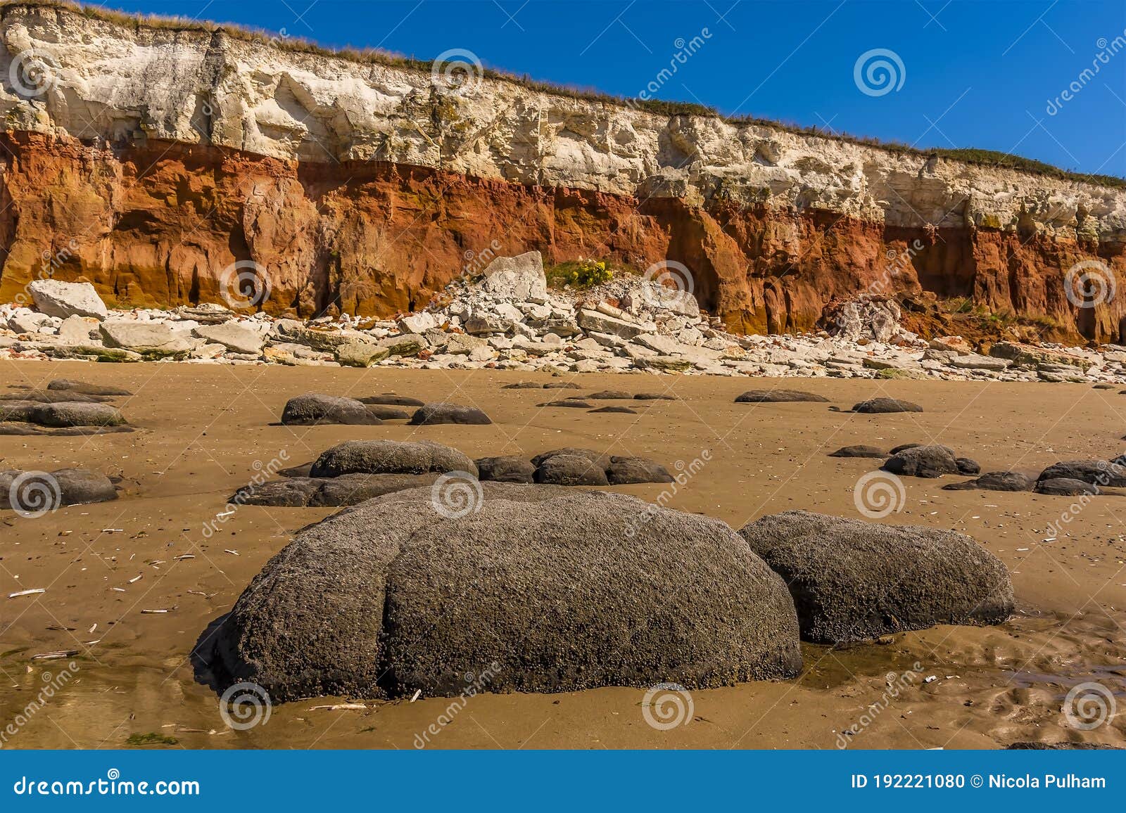 Sea eroded boulders in front of a chalk rock fall at the base of the cliffs at Old Hunstanton, Norfolk, UK
