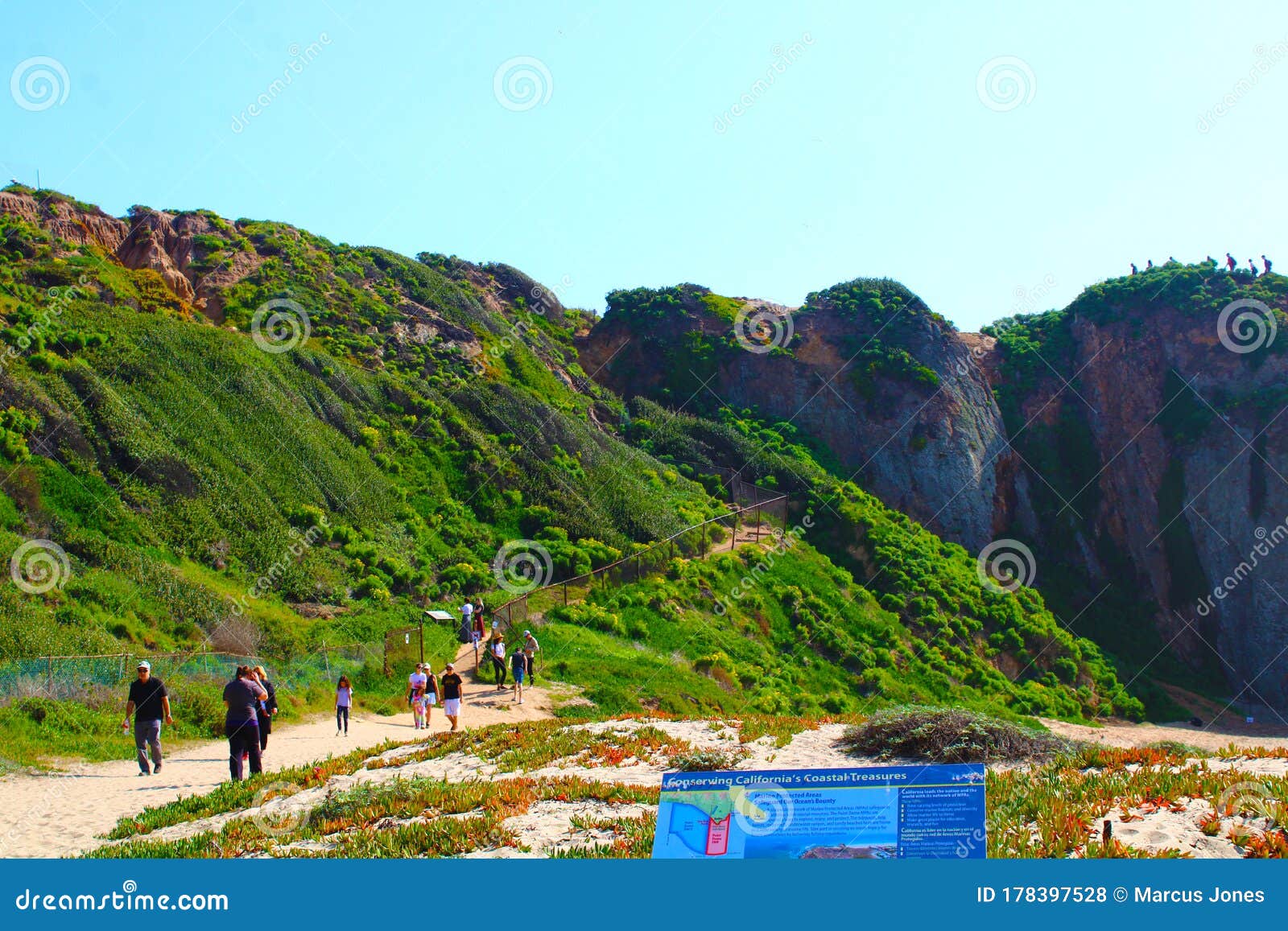 people hiking at the beach with lush green hillsides