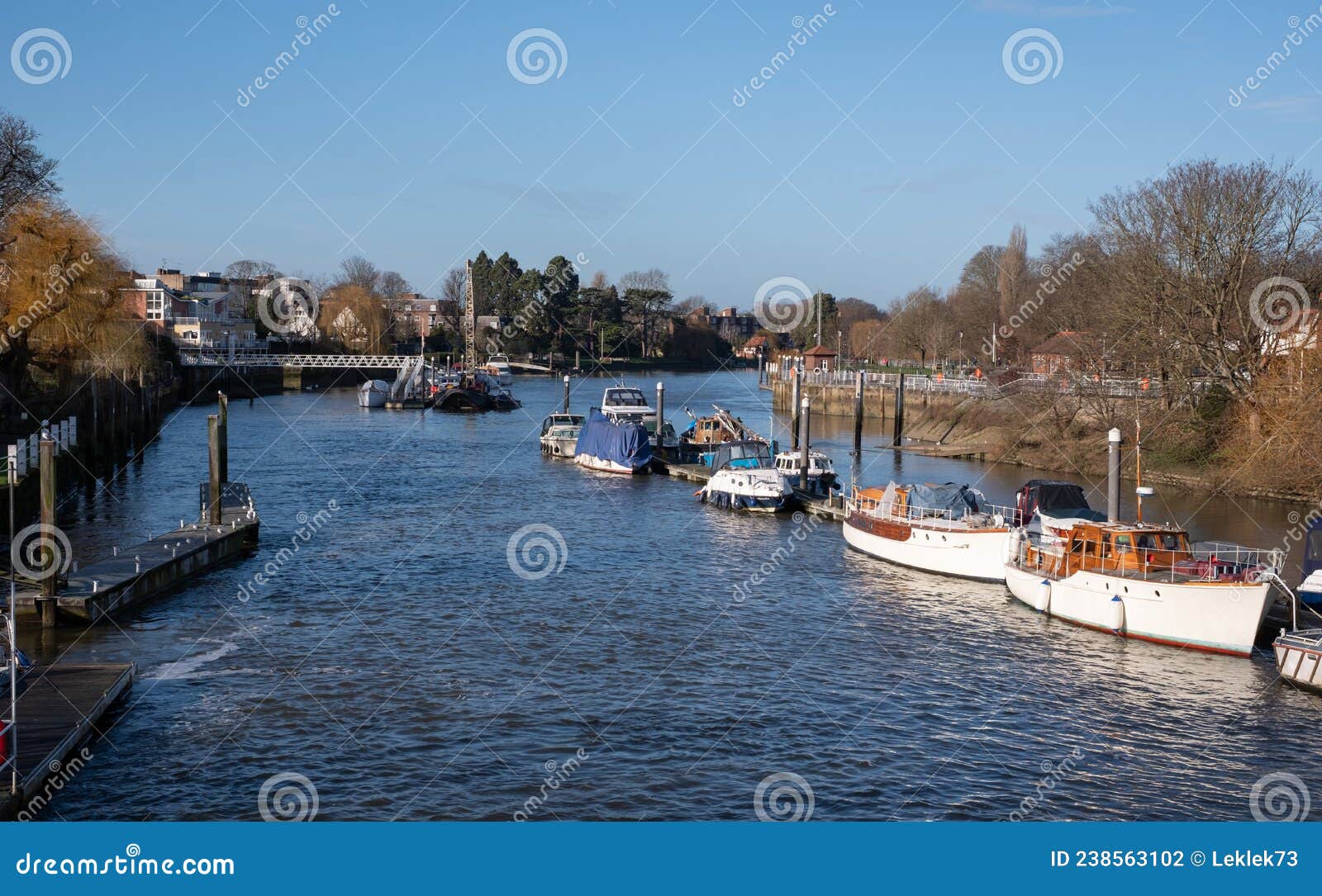 view of the river thames at teddington, west london, uk, with blue sky and boats moored.