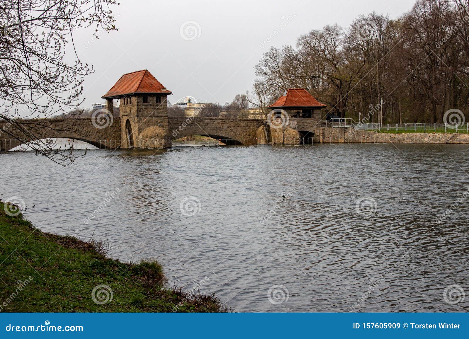 view from the river `weisse elster` in leipzig with trees, bridges and a weir
