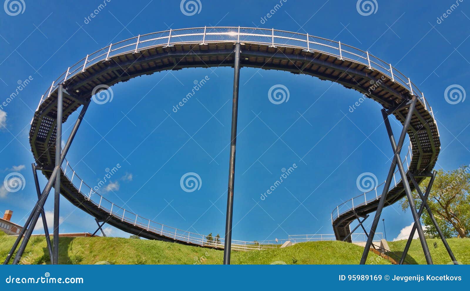 view of a round pedestrian bridge, against a blue sky.