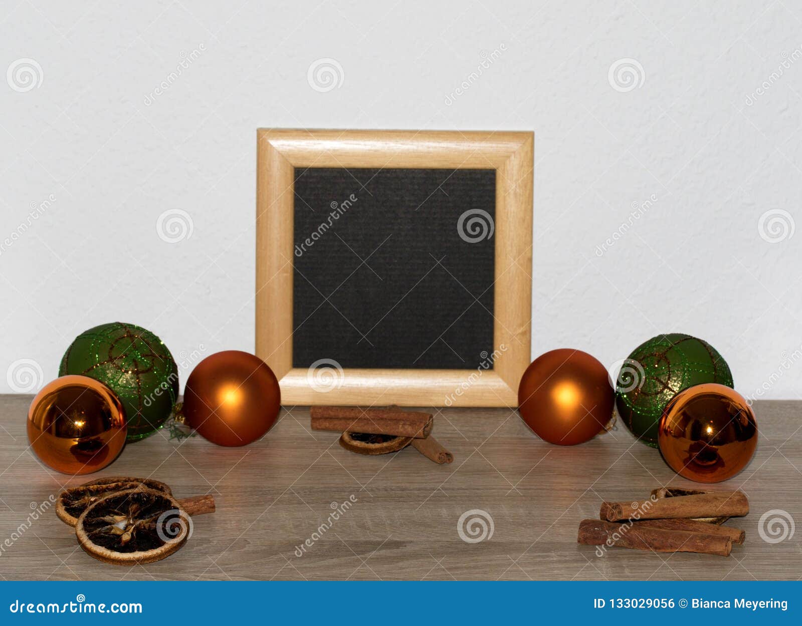 view on some orange and green christmas balls and christmas decoration on a wooden ground and with a white background in the distr