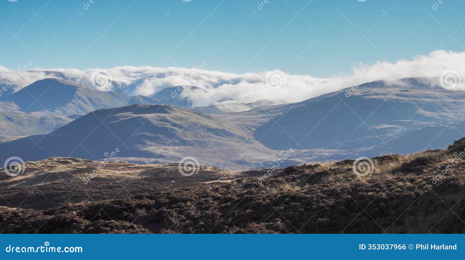 view from top of gowbarrow fell with clouds cascading over fells, lake district