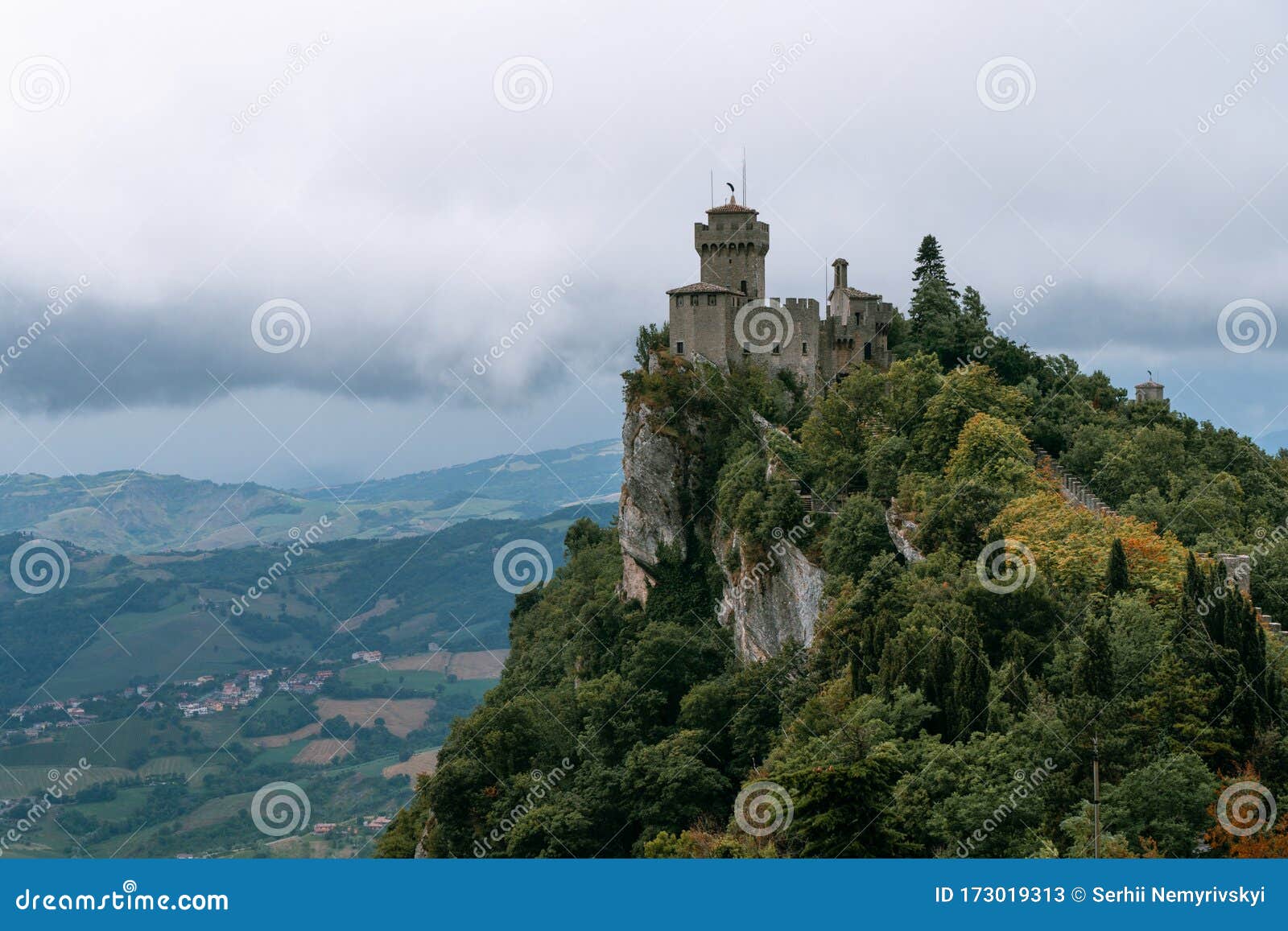 view from the top of the mountain to the medieval fortification. dramatic mystical weather with fog. castle in san marino seconda