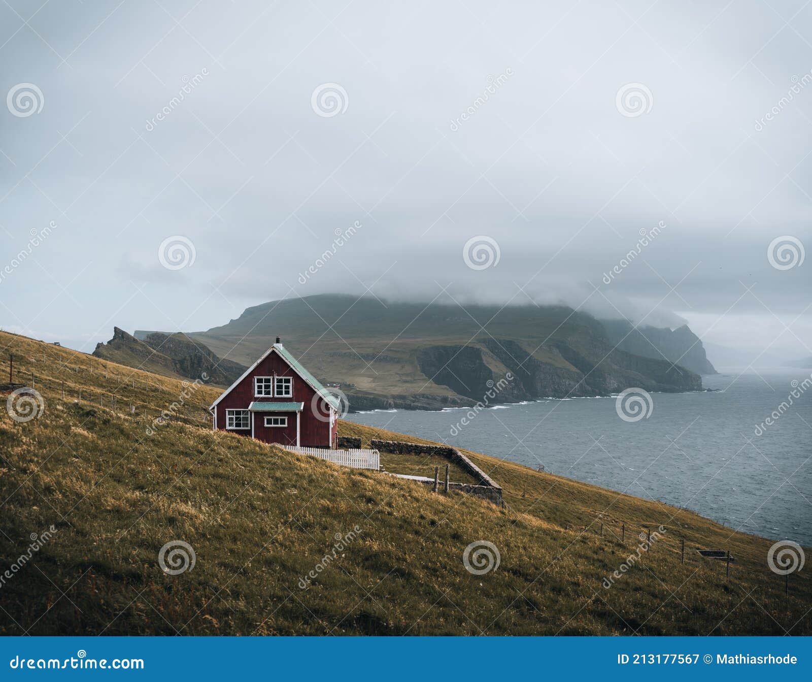 view towards lighthouse on the island of mykines holmur, faroe islandson a cloudy day with view towards atlantic ocean.