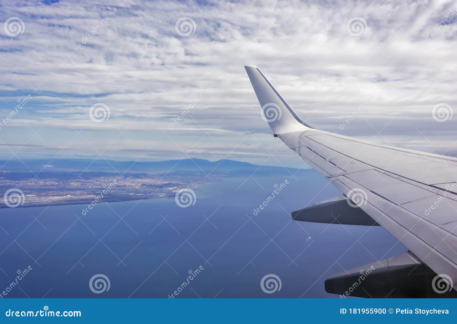 view of the wing of an airplane flying above the clouds at high altitude under a blue sky from the passenger window. in flight