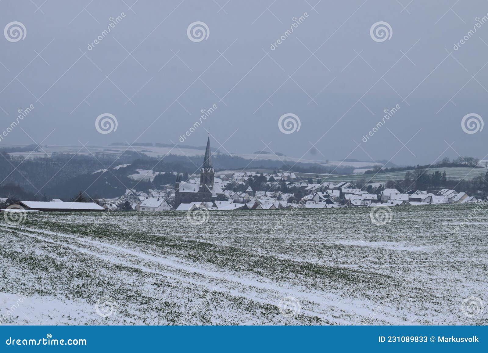 village welling with the dark church tower during winter snow