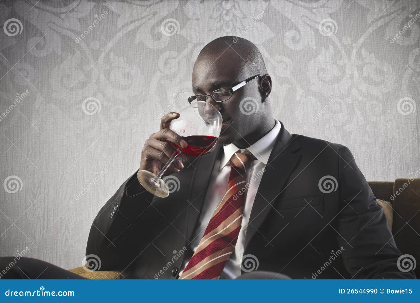 Vinho bebendo do homem de negócios preto. Um homem de negócios preto está bebendo um vidro do vinho vermelho.