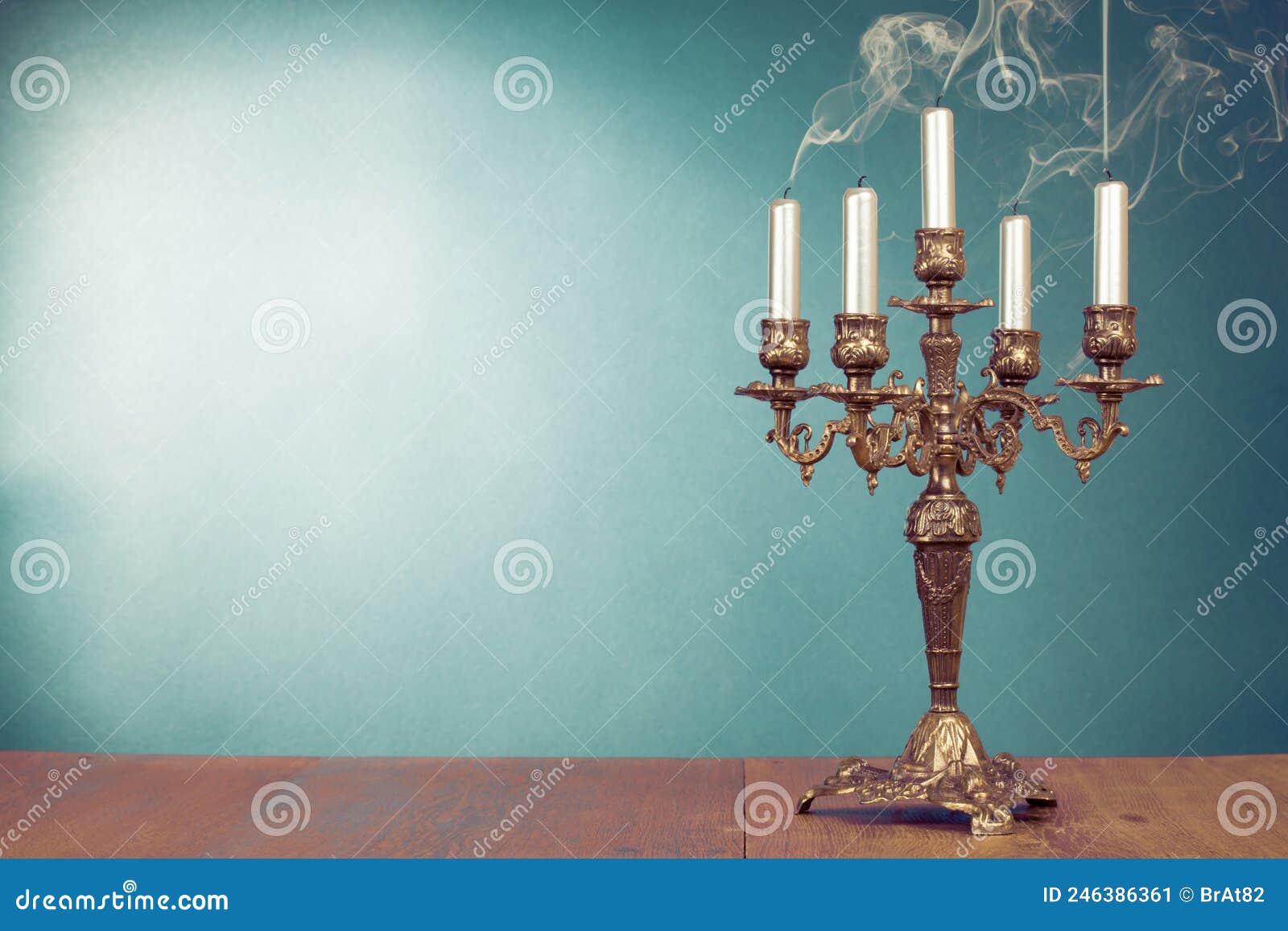 vintage bronze candlestick with five reek candles in front mint blue background