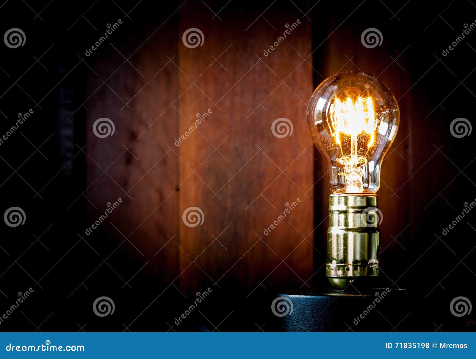 vintage edison light bulb illuminates on wood background.
