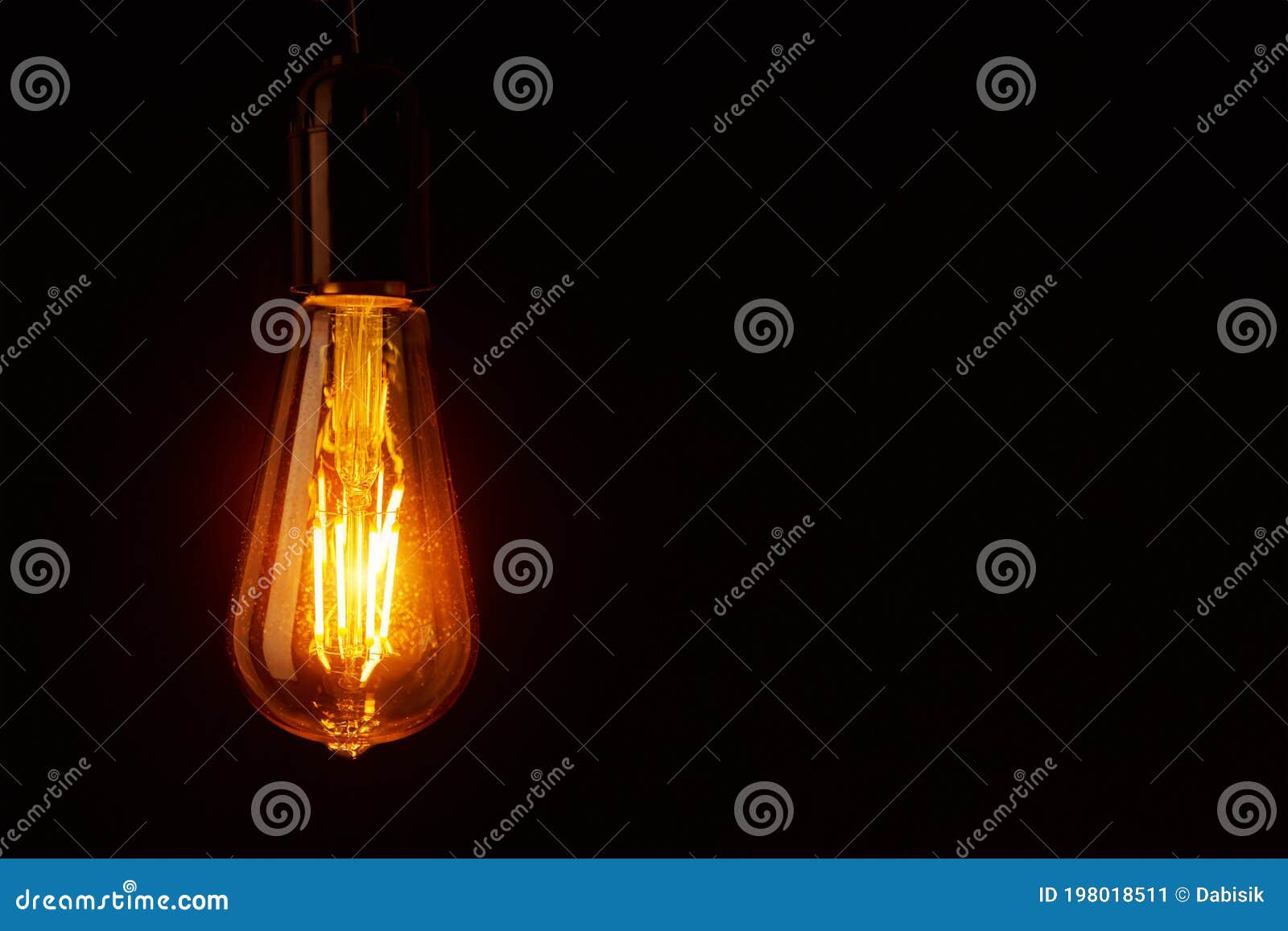 Vintage Light Bulb on Black Background, Copy Space. Glowing Edison Bulb