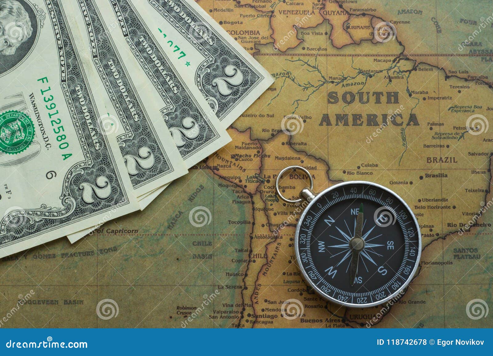 vintage map of south america with two dolor bills and a compass, close-up