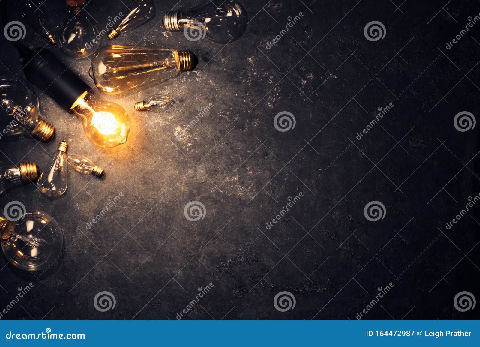 vintage old light bulb glowing on rough dark background surrounded by burnt out bulbs. idea, creativity concept