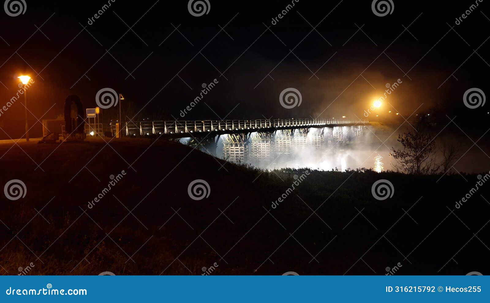 vintage old pedestrian wooden bridge with decorative modern led lights at night engulfed with thick fog and bright city lights