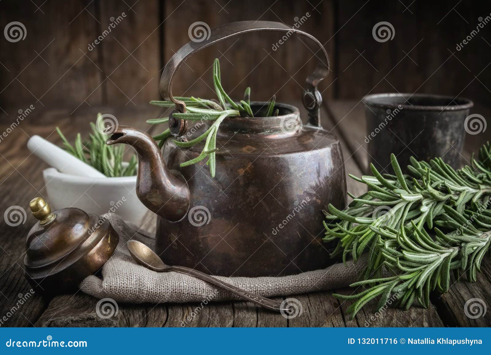 vintage retro teapot, bunch of fresh rosemary herbs, cup of healthy herbal tea and mortar.