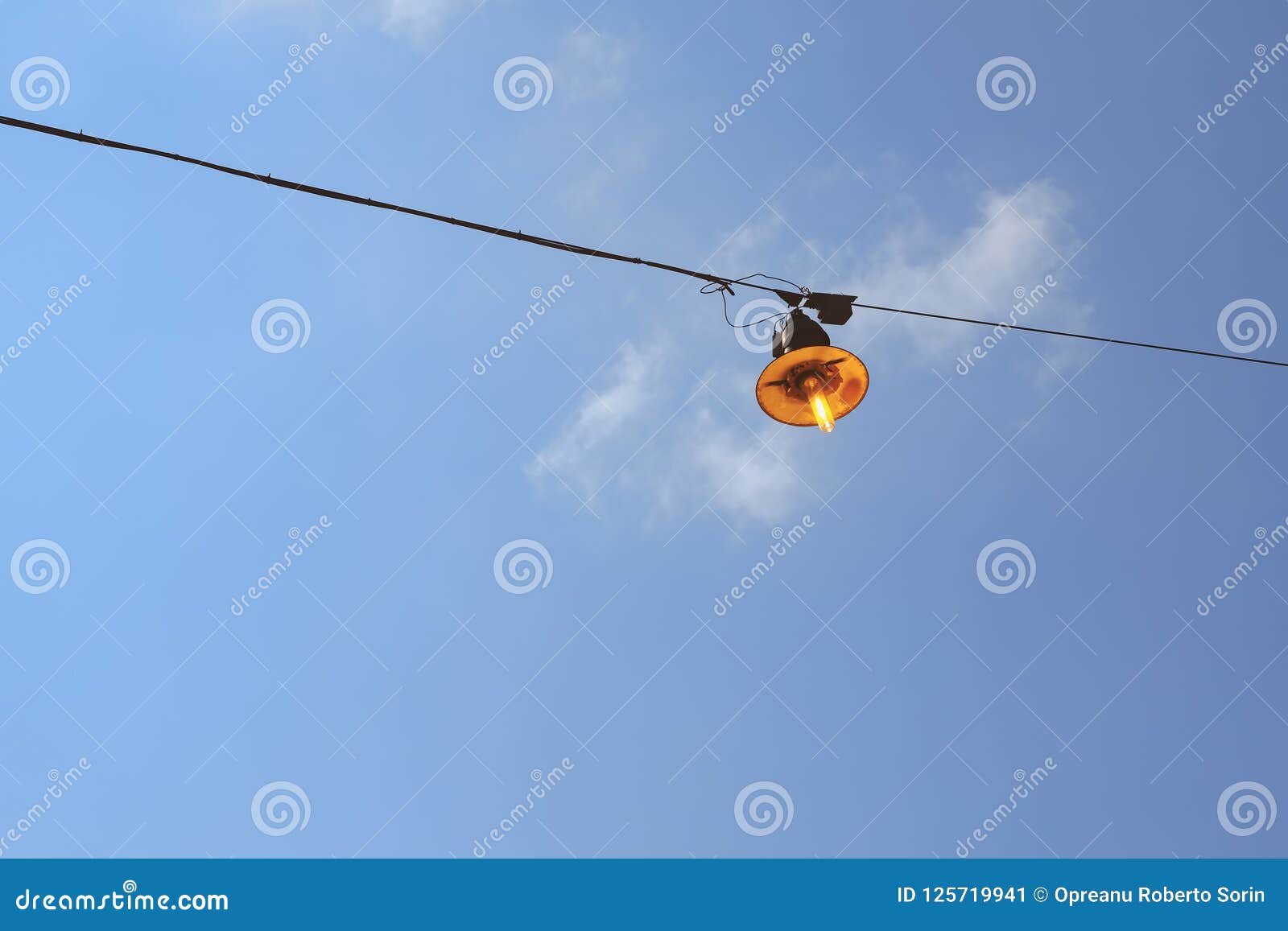 vintage rusty street light lit on the wire on day