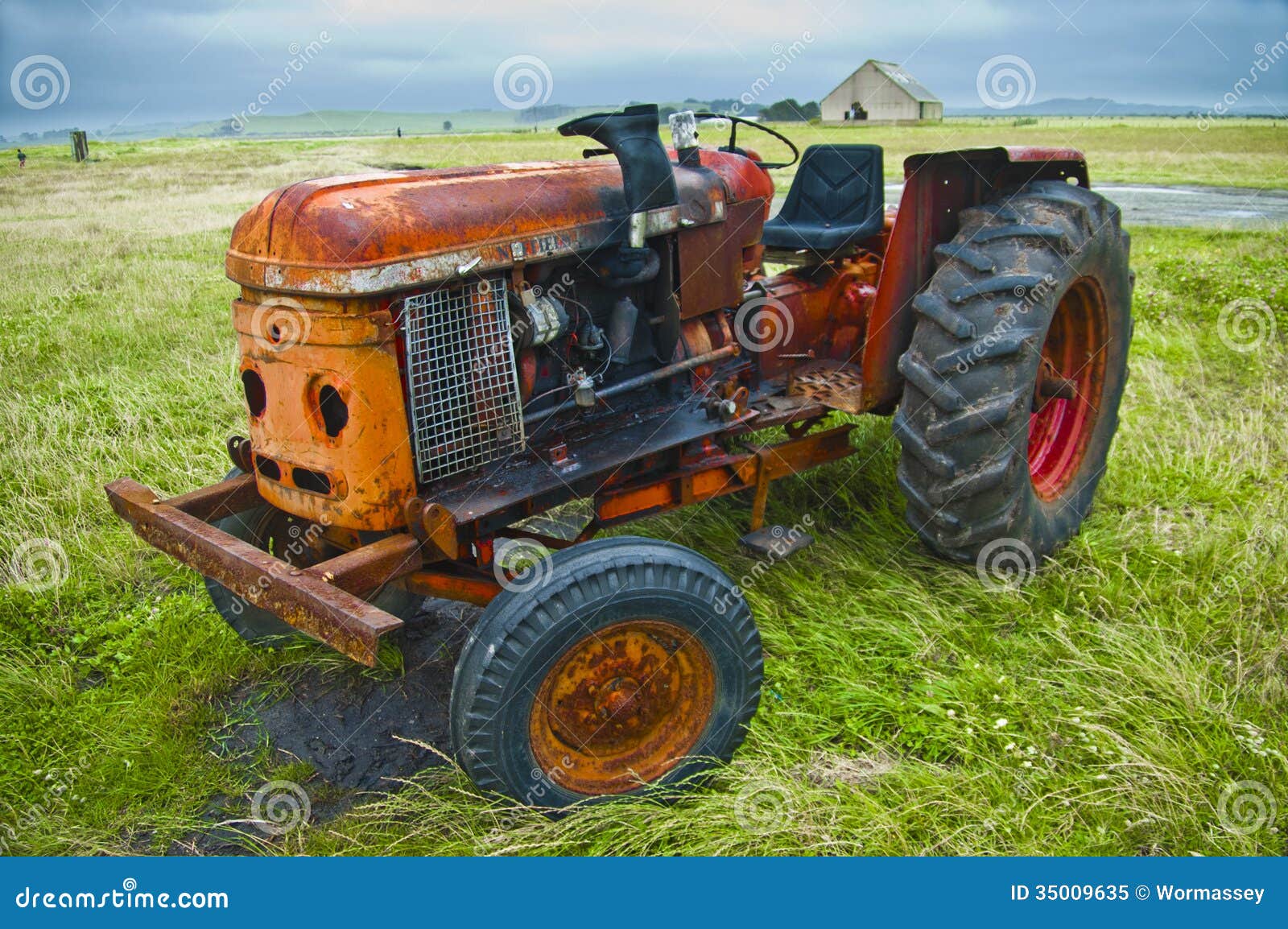 Vintage tractor on a field with a barn on the background