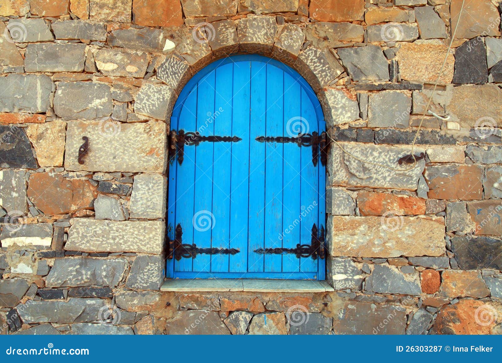 Vintage window with blue close shutters in old stone wall, Crete 