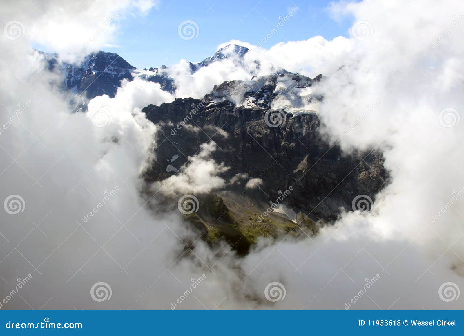 Vista dallo Schilthorn sulle montagne svizzere nevose. Dal terrazzo dello Schilthorn con il suo ristorante di giro di Piz Gloria, reso di fama mondiale da una pellicola del James Bond, voi possono vedere attraverso un foro nelle nubi i picchi nevosi bianchi impressionanti delle montagne del Bernese svizzero Oberland. A sinistra la parte superiore del Grosshorn (3762 m) e nel centro il Breithorn (3782 m). Nella priorità alta la cresta del Tschingelgrat.