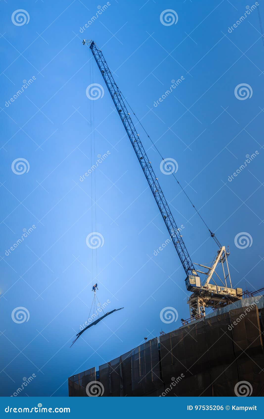 Vista de la construcción del edificio residencial de varios pisos Condominio bajo construcción con la grúa de horca que vira de bordo Sitio de gran altura de la construcción de edificios del rascacielos con la grúa contra el cielo azul brillante