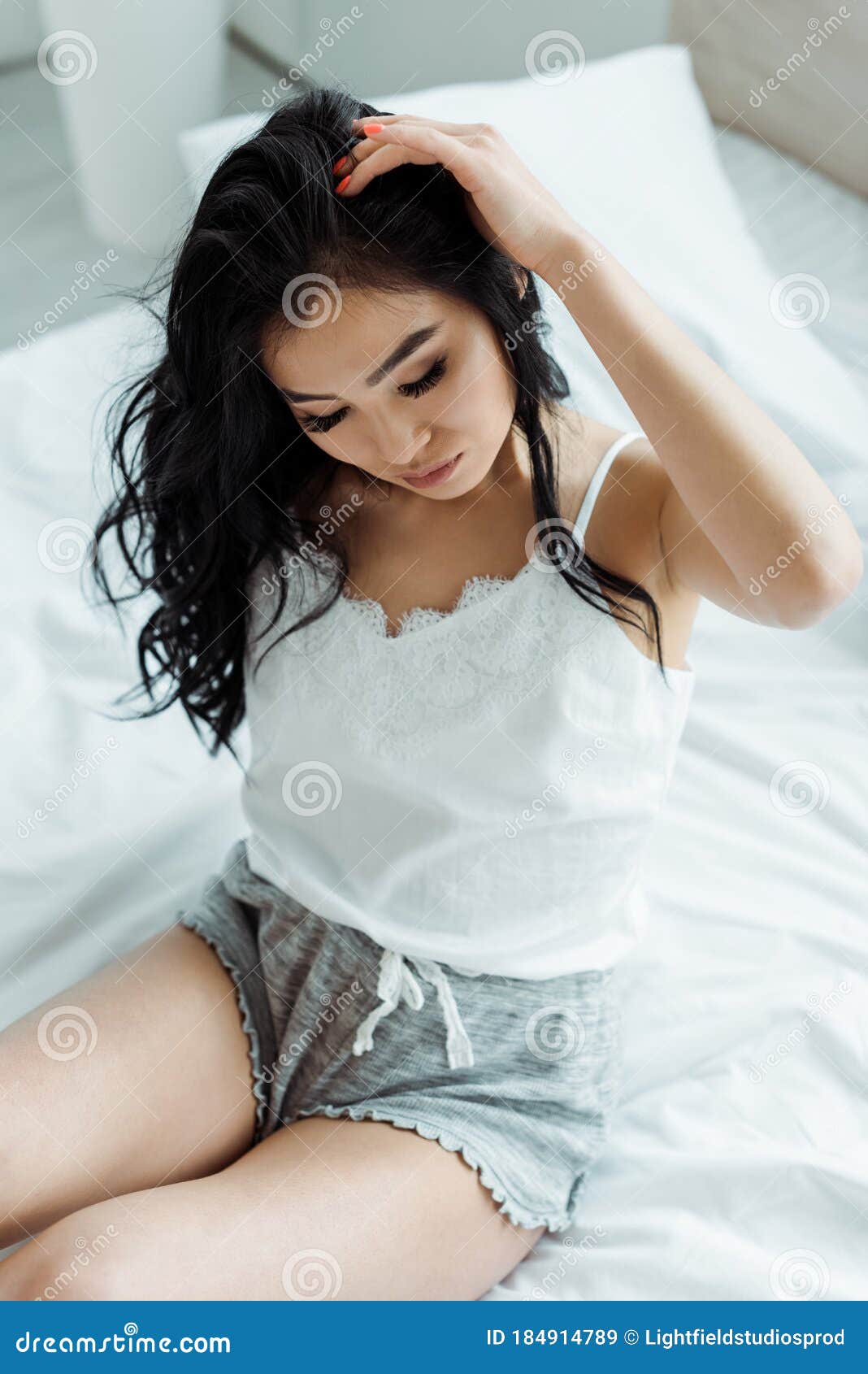 Vista De Uma Mulher Tailandesa Tocando O Cabelo Enquanto Sentada Na Cama Imagem de Stock foto