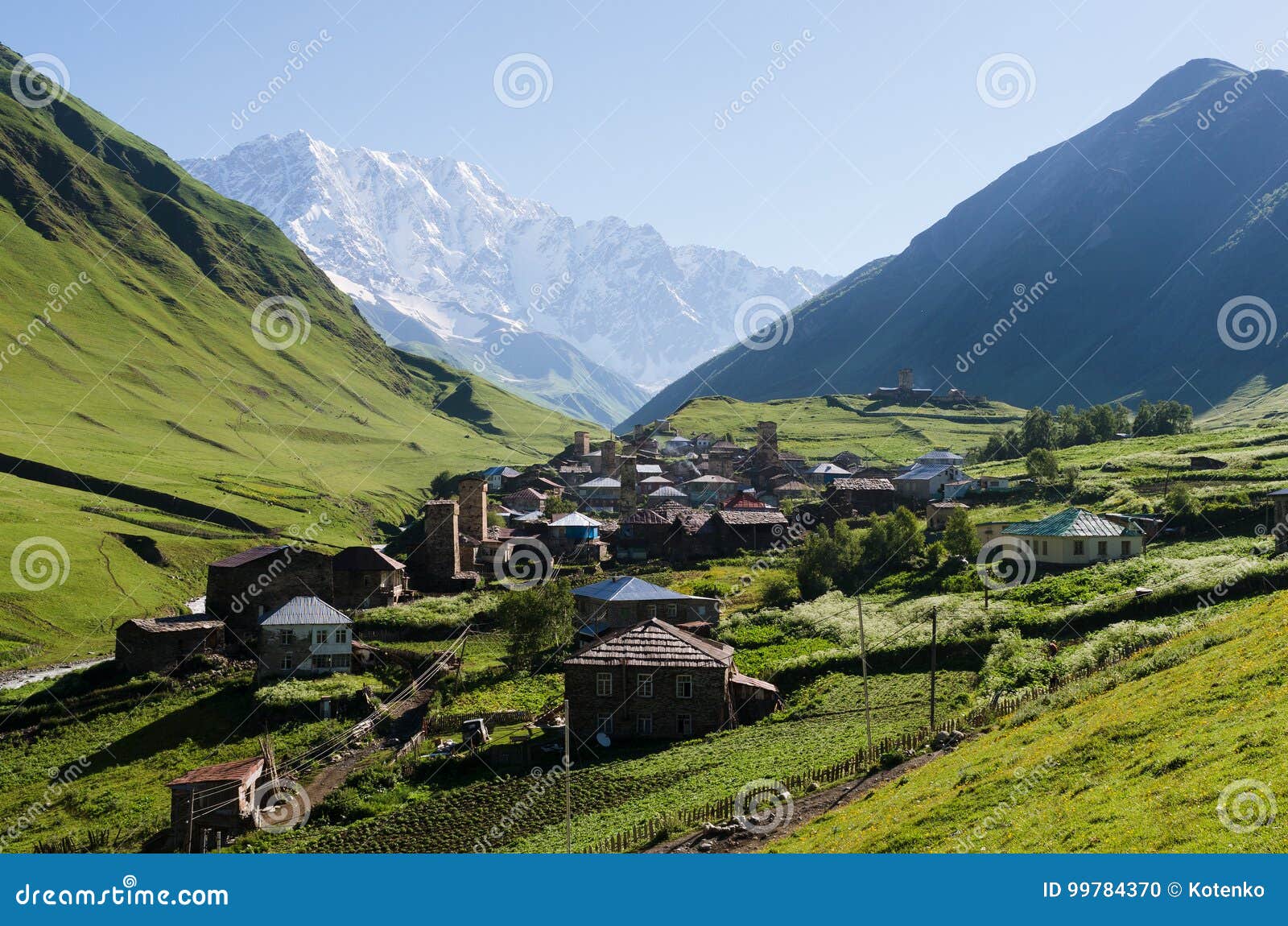 Vista del villaggio di alta montagna di Ushguli in Svaneti, Georgia. Paesaggio della montagna di estate con un picco nevoso e una valle verde Vecchio villaggio con le case di pietra e le torri medievali Comunità di Ushguli Vista del supporto di Shkhara Cresta caucasica principale, Zemo Svaneti, Georgia