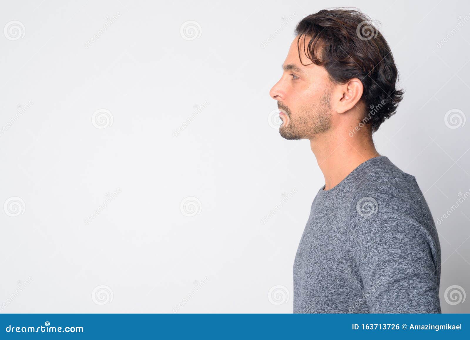 Vista de perfil de um homem bonito com cabelo loiro olhando para a câmera  ao ar livre