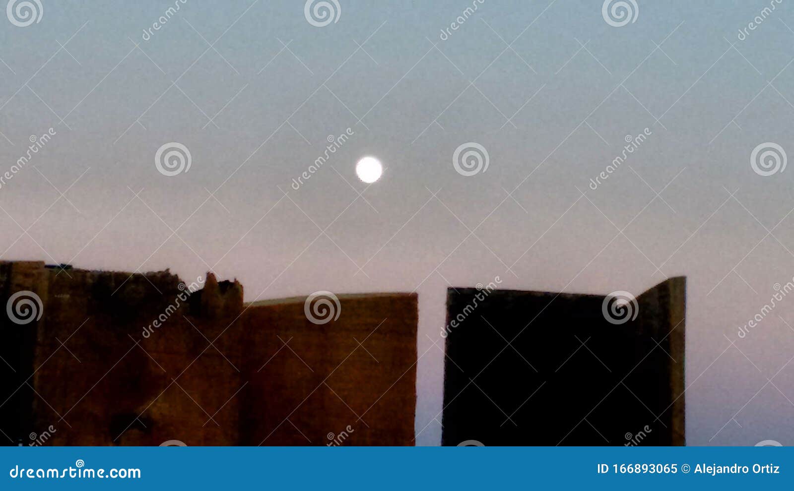 vista en el campo de la luna saliendo por detras de una cerca de madera.
