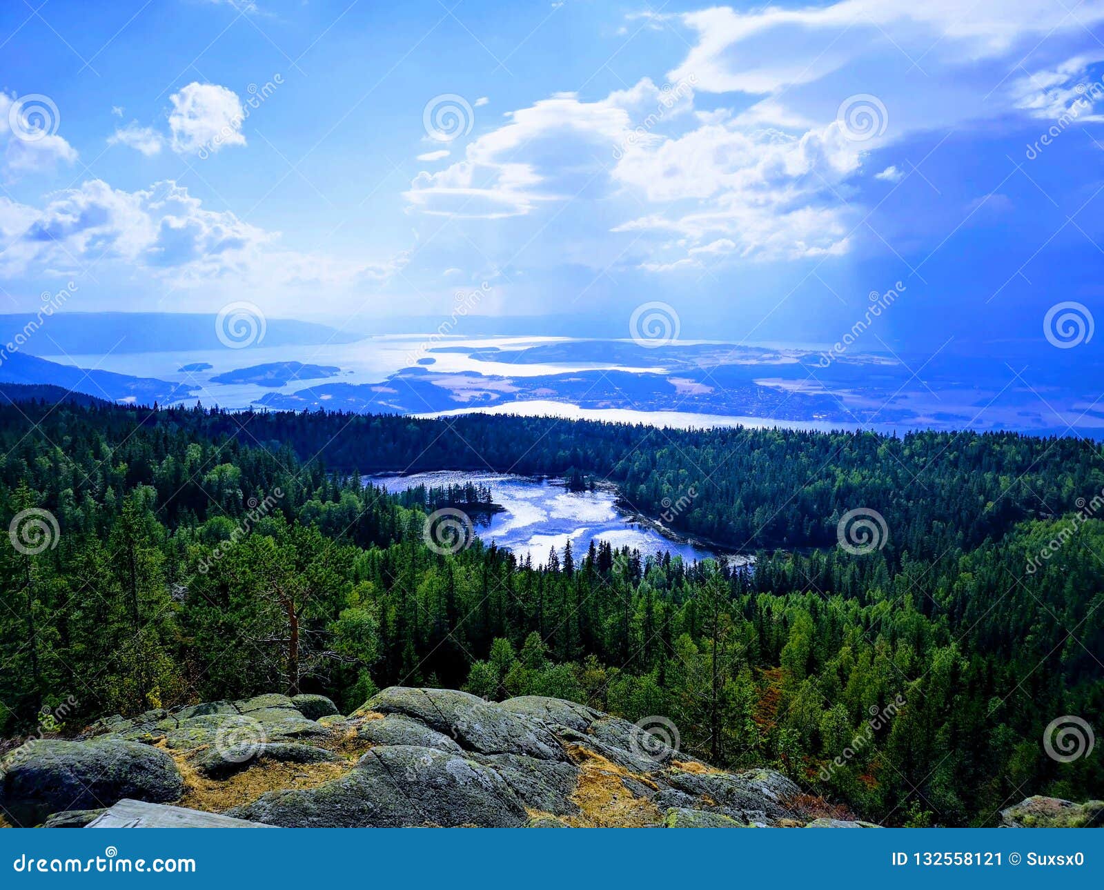 Vista mágica del agua y de las montañas. Una vista clara de montañas y de un lago en la distancia con el sol y el cielo azul que brilla abajo en él