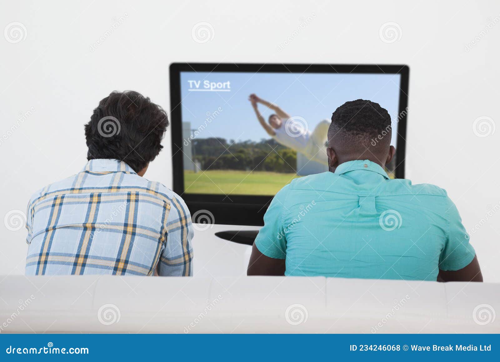 Vista traseira dos homens assistindo a um jogo de futebol na tv e sentado  em um sofá